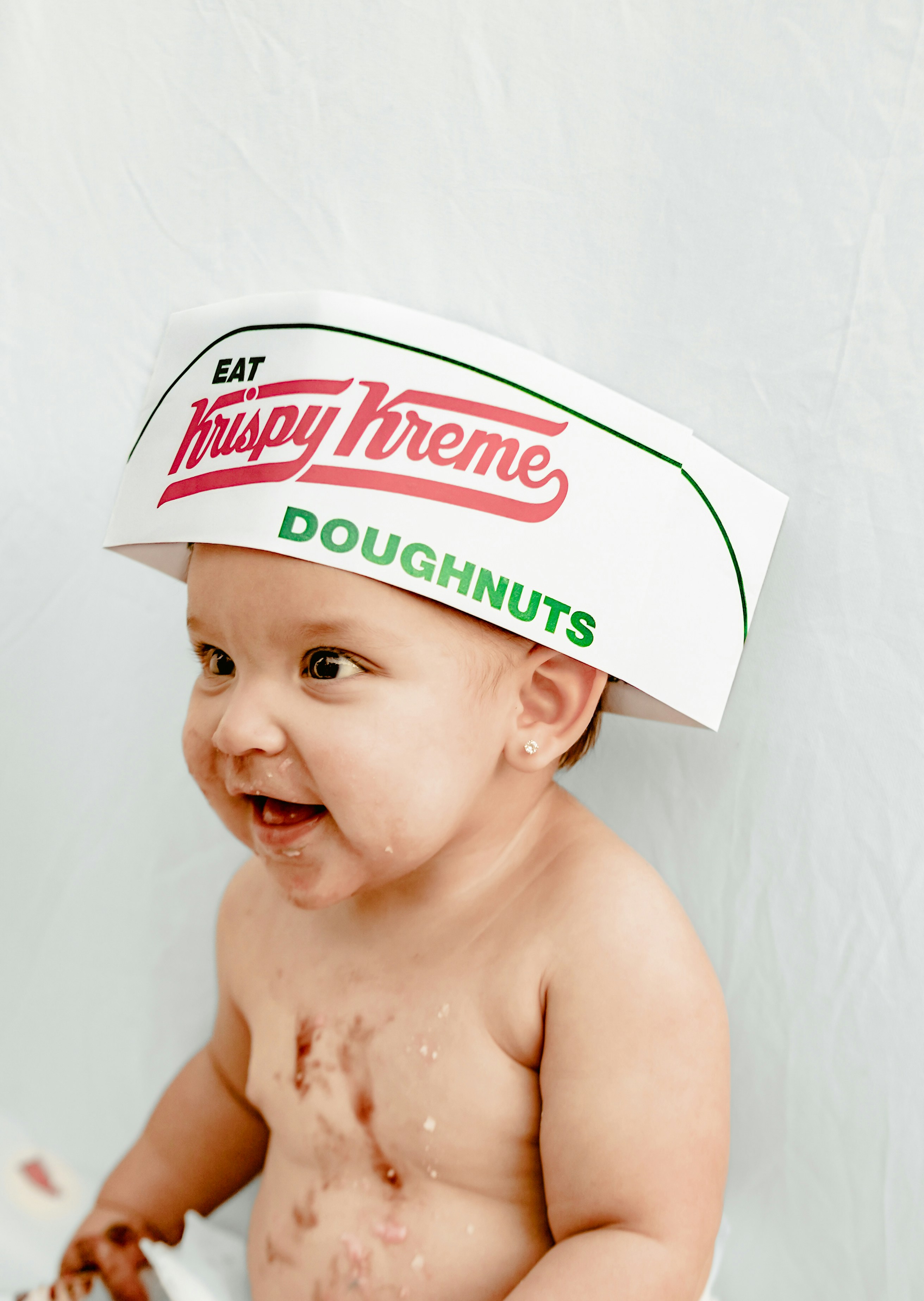 Baby wearing krispy kreme hat with chocolate on face